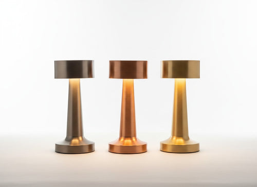 Trois lampes nomades LUMORA Lueur en métal brossé, finitions argent, cuivre et or, design tactile sans fil.