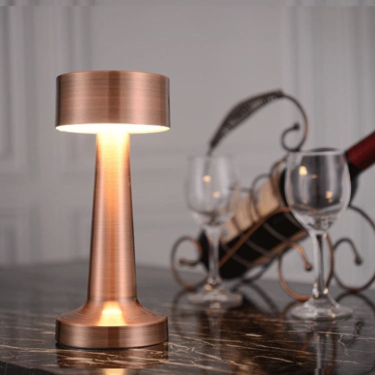 Lampe nomade LUMORA Lueur en métal cuivré brossé, sans fil et tactile, posée sur une table pour une ambiance intime.